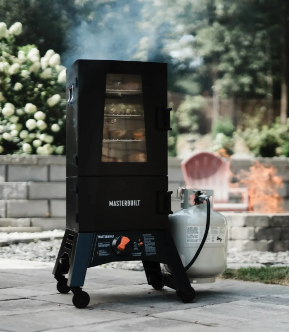 Masterbuilt 40" ThermoTemp XL Propane Smoker, smoking on a backyard patio with propane tank attached