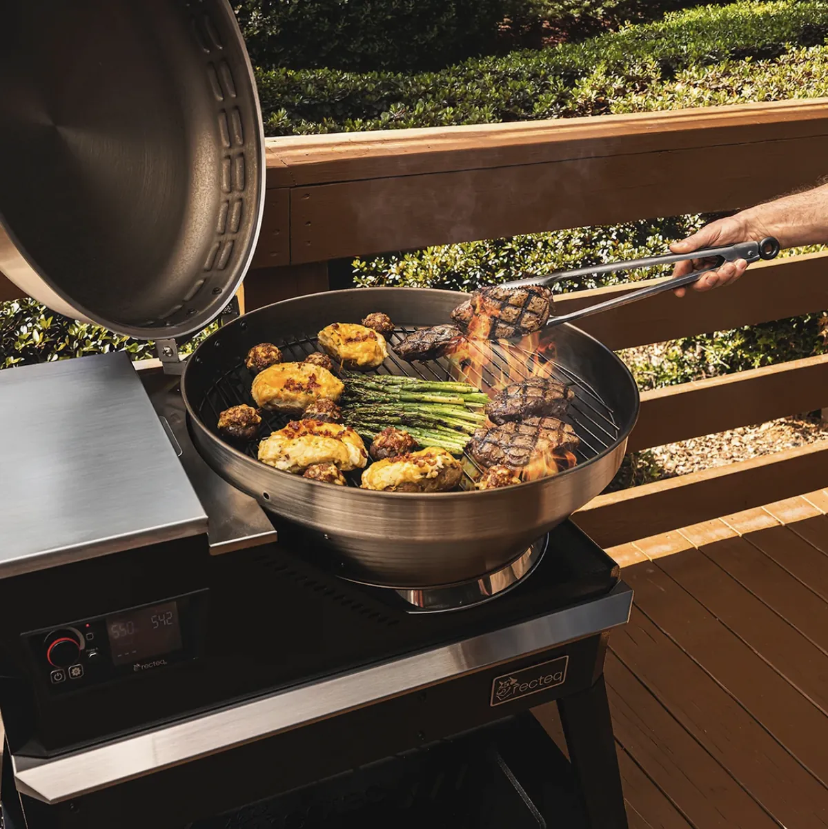 Recteq Bullseye Deluxe 380BD Pellet Grill, searing steaks over open flame with asparagus and stuffed potatoes