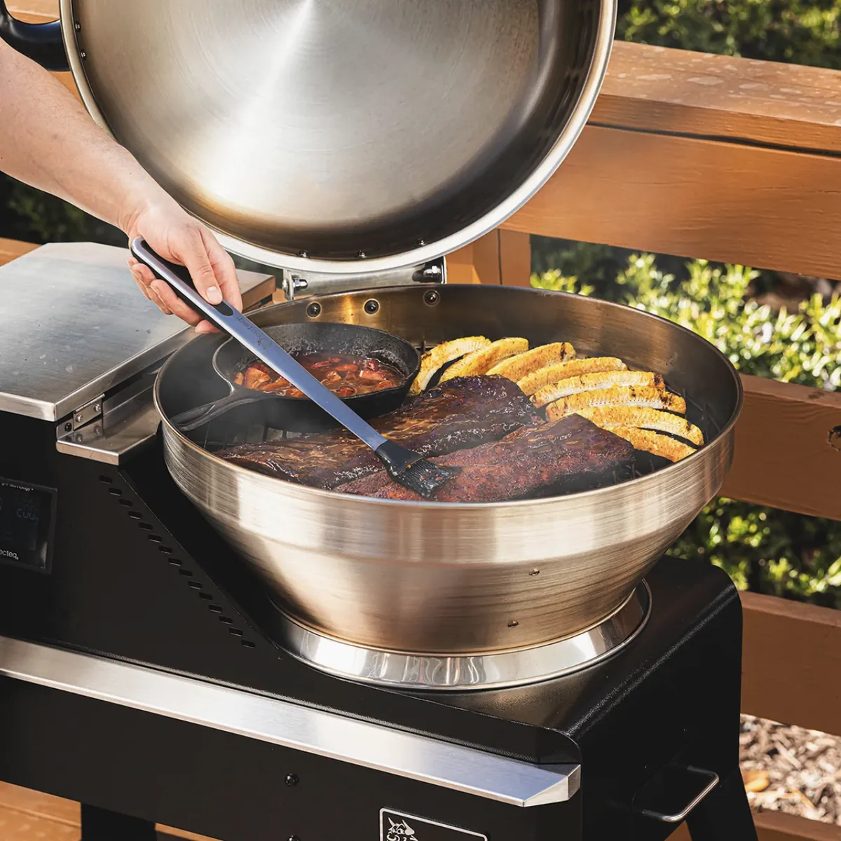 Recteq Bullseye Deluxe 380BD Pellet Grill, basting ribs with corn and a cast iron skillet on the grate