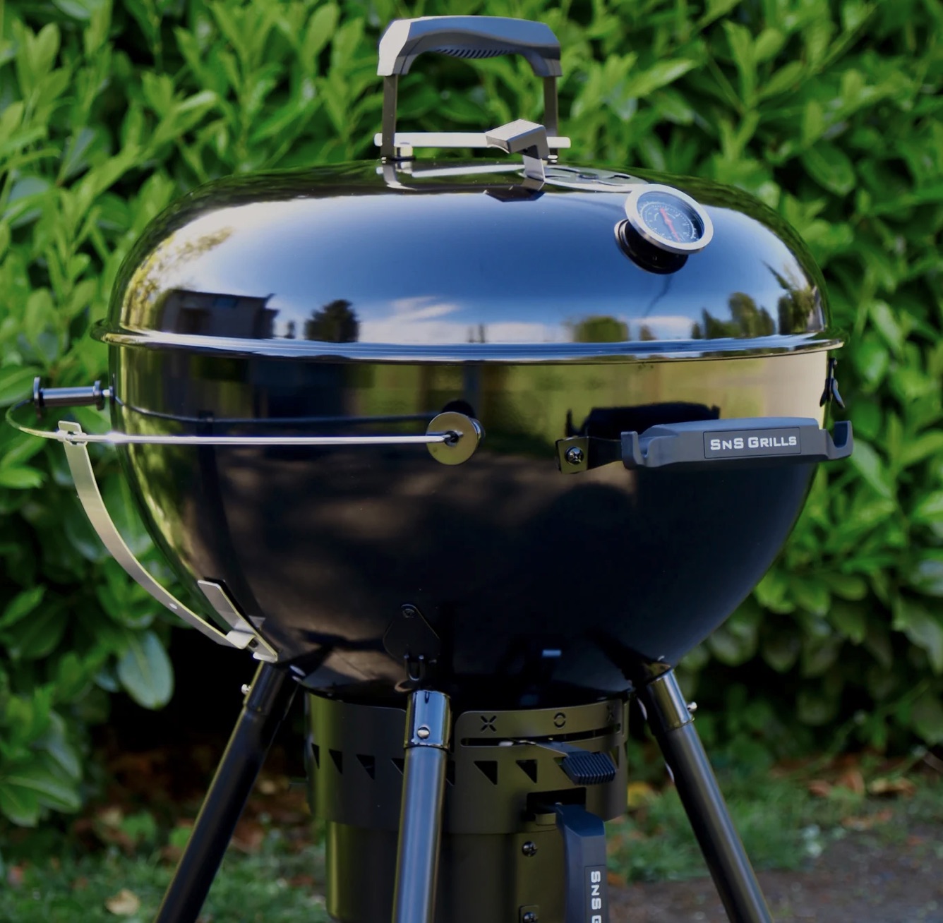 nS Slow 'N Sear Black Edition kettle grill with lid closed in a backyard setting