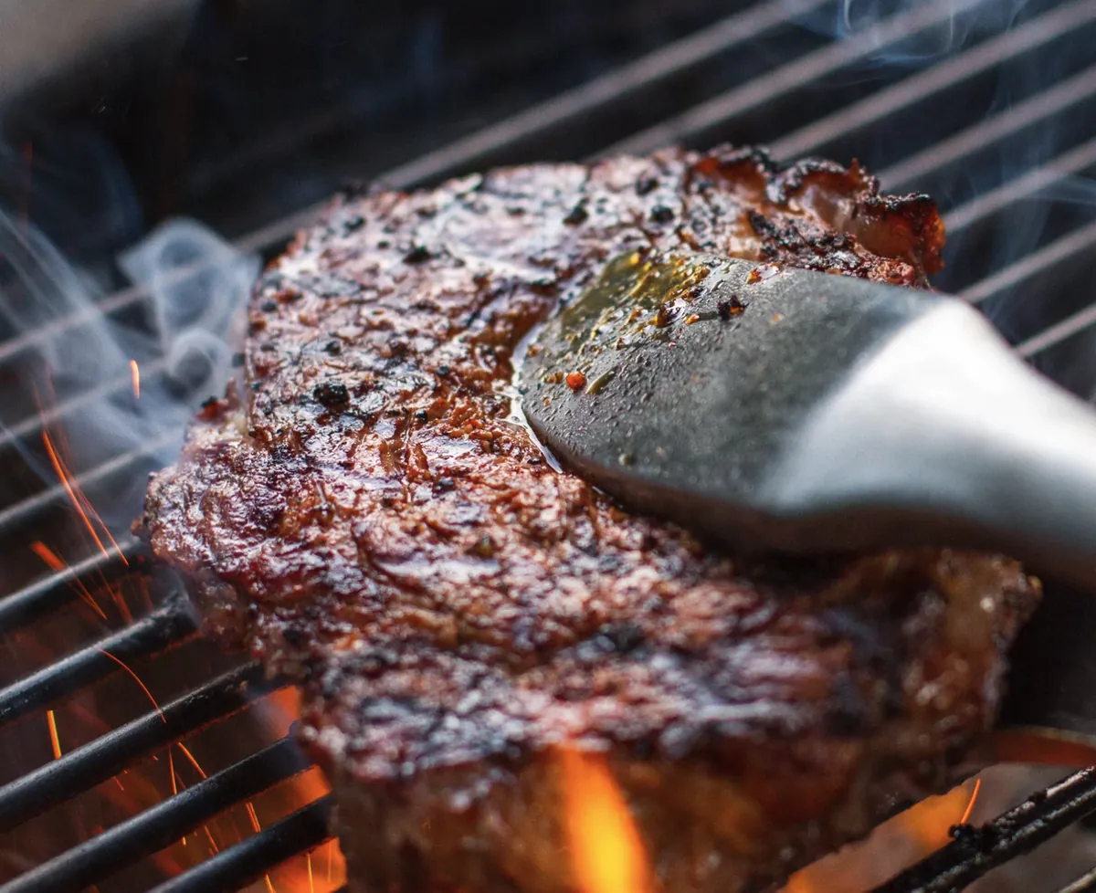 Weber Master-Touch 22" Charcoal Grill, searing a ribeye steak over open flame